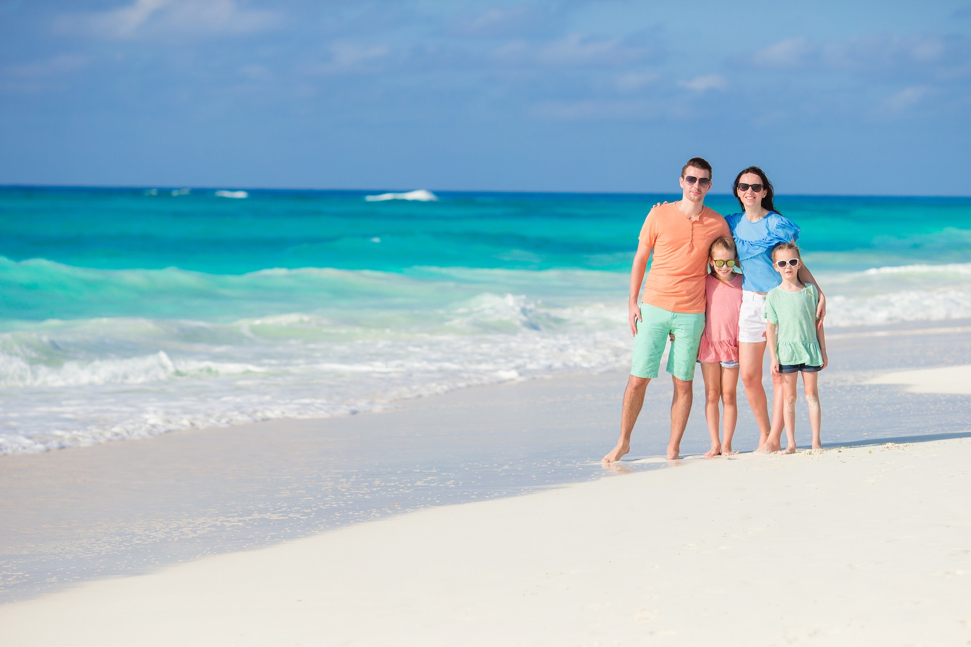 Portrait of happy beautiful family of four on a tropical beach on Carribean vacation